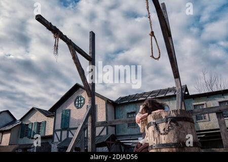 Eine Frau in Fesseln liegt auf den Holzbohlen von Der alte Platz Stockfoto