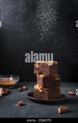 Stapel von Brownies auf schwarzem Hintergrund. Köstliche hausgemachte Schokolade Dessert, Brownie mit Zuckerpulver, Kopie Platz. Stockfoto