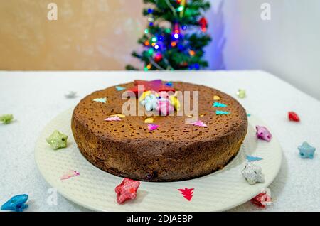 Weihnachten Spezielle Pflaumenkuchen in einem weißen Teller mit Weihnachten Dekorationen und ein Weihnachtsbaum im Hintergrund Stockfoto