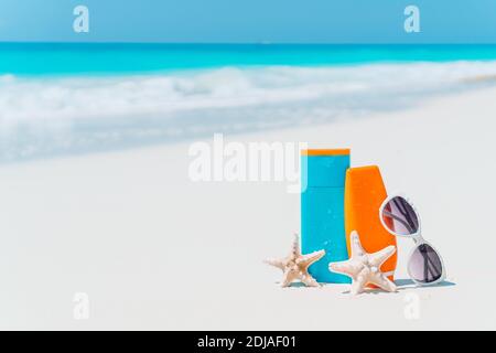 Sonnencreme-Flaschen, Sonnenbrillen, Seesterne am weißen Sandstrand Stockfoto