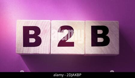 Holzwürfel mit der Abkürzung B2B auf rotem Hintergrund mit Copyspace. Business-to-Business-Konzept Stockfoto