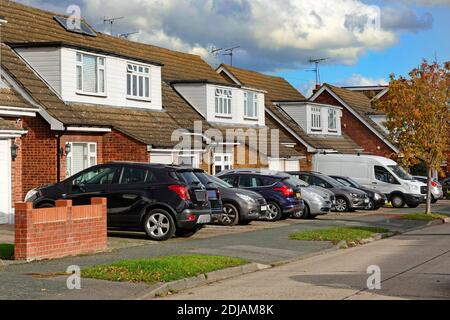 Wohnstraße Szene Parkplatz abseits der Straße & Häuser mit Autos & Van auf ursprünglichen Rasen-Vorgärten jetzt Beton Platz für Fahrzeuge Essex England UK Stockfoto