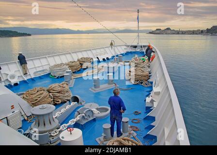 Merchant Navy Seemann & Seeleute arbeiten Bug des Kreuzfahrtschiffes Liner Deck Crew bereit, um Anlegeseil über Bord zu werfen Hafenmole griechische Insel Korfu Stockfoto