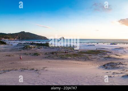 ARRAIAL DO CABO, RIO DE JANEIRO, BRASILIEN - 26. DEZEMBER 2019: Panoramablick auf den Strand Praia Grande bei Sonnenuntergang. Einige Leute genießen das Ende der s Stockfoto