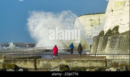 Brighton UK 14. Dezember 2020 - Wanderer beobachten die Wellen, die entlang der Saltdean undercliff an einem windigen Tag in der Nähe von Brighton heute bei Flut einstürzen. Die Wettervorhersage ist für stärkere Winde und Duschen, um über Teile von Großbritannien zu verbreiten, aber mit Temperaturen, die wärmer als in den letzten Tagen sind : Credit Simon Dack / Alamy Live News Stockfoto