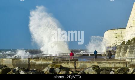 Brighton UK 14. Dezember 2020 - Wanderer beobachten die Wellen, die entlang der Saltdean undercliff an einem windigen Tag in der Nähe von Brighton heute bei Flut einstürzen. Die Wettervorhersage ist für stärkere Winde und Duschen, um über Teile von Großbritannien zu verbreiten, aber mit Temperaturen, die wärmer als in den letzten Tagen sind : Credit Simon Dack / Alamy Live News Stockfoto