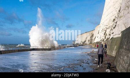 Brighton UK 14. Dezember 2020 - Wanderer beobachten und ausweichen die Wellen in einem windigen Tag entlang Saltdean undercliff Spaziergang an der Küste in der Nähe von Brighton bei Flut . Die Wettervorhersage ist für stärkere Winde und Duschen, um über Teile von Großbritannien zu verbreiten, aber mit Temperaturen, die wärmer als in den letzten Tagen sind : Credit Simon Dack / Alamy Live News Stockfoto