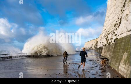 Brighton UK 14. Dezember 2020 - EIN Läufer und Radfahrer beobachten und ausweichen die Wellen in einem windigen Tag auf Saltdean undercliff Spaziergang an der Küste in der Nähe von Brighton bei Flut . Die Wettervorhersage ist für stärkere Winde und Duschen, um über Teile von Großbritannien zu verbreiten, aber mit Temperaturen, die wärmer als in den letzten Tagen sind : Credit Simon Dack / Alamy Live News Stockfoto