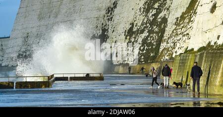 Brighton UK 14. Dezember 2020 - Wanderer beobachten und ausweichen die Wellen in einem windigen Tag auf Saltdean undercliff Spaziergang an der Küste in der Nähe von Brighton bei Flut . Die Wettervorhersage ist für stärkere Winde und Duschen, um über Teile von Großbritannien zu verbreiten, aber mit Temperaturen, die wärmer als in den letzten Tagen sind : Credit Simon Dack / Alamy Live News Stockfoto