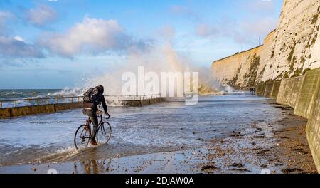 Brighton UK 14. Dezember 2020 - EIN Radfahrer pflügt durch das Wasser, während die Wellen an einem windigen Tag bei Saltdean undercliff Walk an der Strandpromenade nahe Brighton bei Flut einstürzen. Die Wettervorhersage ist für stärkere Winde und Duschen, um über Teile von Großbritannien zu verbreiten, aber mit Temperaturen, die wärmer als in den letzten Tagen sind : Credit Simon Dack / Alamy Live News Stockfoto
