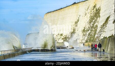 Brighton UK 14. Dezember 2020 - Wanderer beobachten und ausweichen die Wellen in einem windigen Tag auf Saltdean undercliff Spaziergang an der Küste in der Nähe von Brighton bei Flut . Die Wettervorhersage ist für stärkere Winde und Duschen, um über Teile von Großbritannien zu verbreiten, aber mit Temperaturen, die wärmer als in den letzten Tagen sind : Credit Simon Dack / Alamy Live News Stockfoto