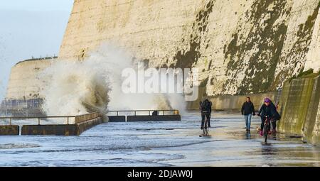 Brighton UK 14. Dezember 2020 - Wanderer und Radfahrer beobachten und ausweichen die Wellen an einem windigen Tag entlang Saltdean undercliff Walk an der Küste in der Nähe von Brighton bei Flut . Die Wettervorhersage ist für stärkere Winde und Duschen, um über Teile von Großbritannien zu verbreiten, aber mit Temperaturen, die wärmer als in den letzten Tagen sind : Credit Simon Dack / Alamy Live News Stockfoto