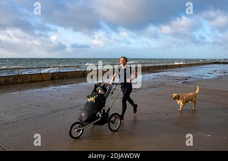 Brighton UK 14. Dezember 2020 - EIN Läufer genießt das windige Wetter entlang Saltdean undercliff Walk an der Küste in der Nähe von Brighton heute bei Flut. Die Wettervorhersage ist für stärkere Winde und Duschen, um über Teile von Großbritannien zu verbreiten, aber mit Temperaturen, die wärmer als in den letzten Tagen sind : Credit Simon Dack / Alamy Live News Stockfoto