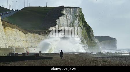 Brighton UK 14. Dezember 2020 - Spaziergänger beobachten die Wellen an einem windigen Tag am Saltdean Strand in der Nähe von Brighton heute bei Flut . Die Wettervorhersage ist für stärkere Winde und Duschen, um über Teile von Großbritannien zu verbreiten, aber mit Temperaturen, die wärmer als in den letzten Tagen sind : Credit Simon Dack / Alamy Live News Stockfoto
