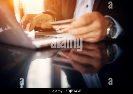 Nahaufnahme eines männlichen Geschäftsmannes Hände mit einem Laptop und halten Bankkarte. Stockfoto