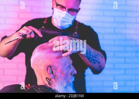 Hipster Mann immer Haare geschnitten im Vintage Friseur Shop während Tragen von Gesichtsschutzmasken für Coronavirus Prävention - Fokus auf Bärtiger Kerl Ohr Stockfoto