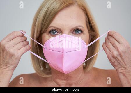 Ältere Frau posiert auf grauem Hintergrund Stockfoto