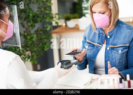 Ältere Dame trägt eine Maske in Maniküre Salon Stockfoto