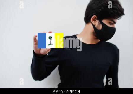 Malaiischer Mann tragen ganz schwarz mit Gesichtsmaske halten Penang Flagge in der Hand isoliert auf weißem Hintergrund. Staaten und Bundesgebiete von Malaysia Coronavirus Stockfoto