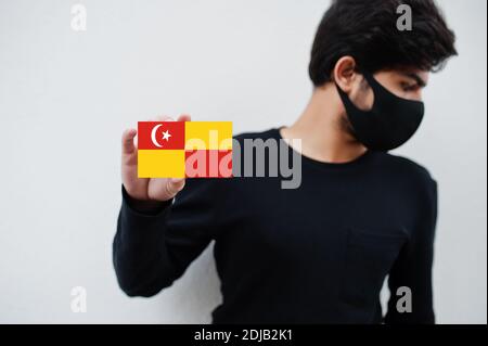 Malaiischer Mann tragen ganz schwarz mit Gesichtsmaske halten Selangor Flagge in der Hand isoliert auf weißem Hintergrund. Staaten und Bundesgebiete von Malaysia coronaviru Stockfoto