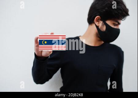 Malaiischer Mann tragen ganz schwarz mit Gesichtsmaske halten Kuala Lumpur Flagge in der Hand isoliert auf weißem Hintergrund. Staaten und Bundesgebiete von Malaysia corona Stockfoto