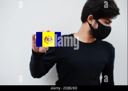 Malaiischer Mann tragen ganz schwarz mit Gesichtsmaske halten Putrajaya Flagge in der Hand isoliert auf weißem Hintergrund. Staaten und Bundesgebiete von Malaysia coronavir Stockfoto