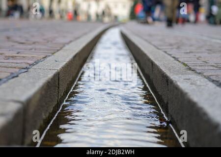 Der Freiburger Bächle Wasserlauf in Nahaufnahme und selektivem Fokus Erdgeschossaufnahme mit Fußgängern, die auf der Straße vorbei gehen Stockfoto