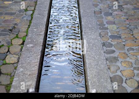 Nahaufnahme des Baches Bächle Rill, in der asphaltierten Straße von Freiburg, Deutschland Stockfoto