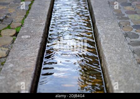 Nahaufnahme des Baches Bächle Rill, in der asphaltierten Straße von Freiburg, Deutschland Stockfoto