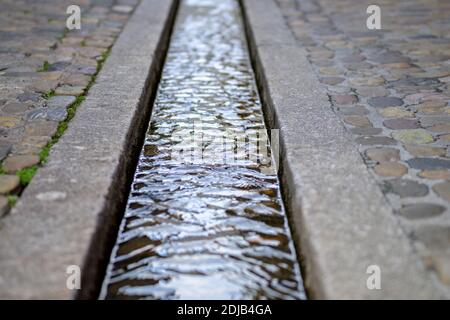 Wasserstrahl in formalisierten Rill in Pflaster der Straße. Berühmte kleine Wassertrichter - Bächle, in der Stadt Freiburg, Deutschland Stockfoto