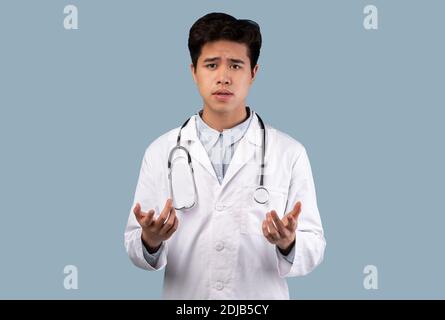 Asian Kerl im medizinischen Mantel im Gespräch mit Kamera, gestikuling Stockfoto