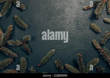 Minimale weihnachtliche Komposition mit Tannenzweig auf dunklem Hintergrund. Horizontale obere Komposition, flache Lage, Draufsicht. Stockfoto