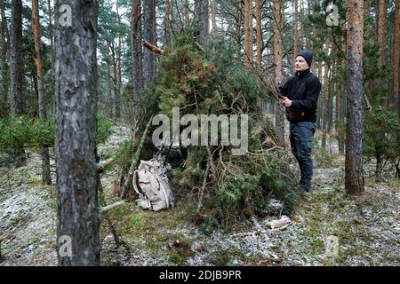 Wildniss Survival Camp - Mann baut Baumzweig Hütte in Wald im Winter Stockfoto