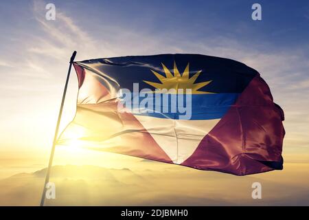 Die Flagge von Antigua und Barbuda winkt auf dem Sonnenaufgangsnebel Nebel Stockfoto