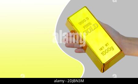 Menschliche Hand hält den Goldbalken auf gelb und grau Hintergrund Stockfoto