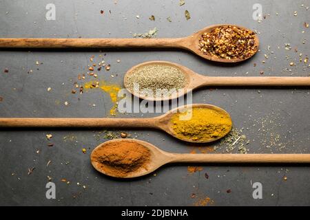 Verschiedene Gewürze auf Holzlöffeln, auf Steintisch Stockfoto