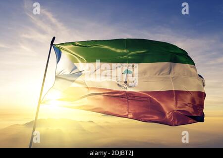 Äquatorialguinea Flagge winkt auf der Oberseite Sonnenaufgang Nebel Stockfoto