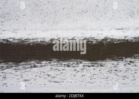 Instandhaltung der Straßen und Gehwege im Winter. Schneebedeckter Gehweg und menschliche Fußabdrücke auf Fußgängerweg. Luftaufnahme Stockfoto