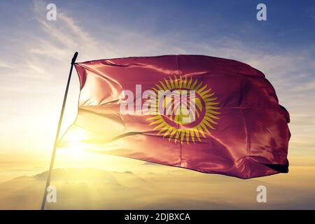 Kirgisistan Flagge winkt auf der Oberseite Sonnenaufgang Nebel Stockfoto