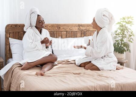 Glückliche schwarze Frauen trinken Tee und reden, gute Zeit zu haben Stockfoto