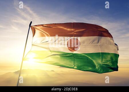 Niger Flagge winkt auf der Oberseite Sonnenaufgang Nebel Stockfoto