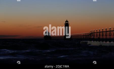 Grand Haven South Pier Leuchtturm bei Sonnenuntergang am Lake Michigan, an einem windigen Tag Stockfoto