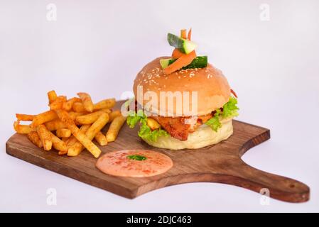 burger und Pommes auf Holzbasis. burger mit Salat, Fleisch und Pommes und Sauce auf Holzplatte. Stockfoto