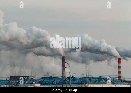 Industriekamine mit Rauch auf dem grauen Himmel Hintergrund. Smokestack Verschmutzung in der Luft als Umweltproblem Stockfoto