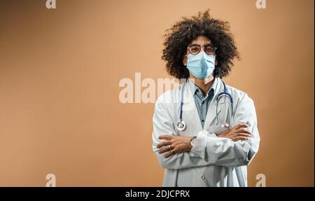 Glücklich reifen Mann Arzt mit Gesichtsmaske im Stehen im Studio, Coronavirus Konzept. Stockfoto