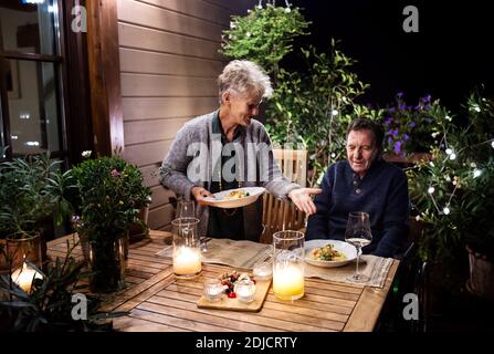 Ein älteres Paar im Rollstuhl, das abends auf der Terrasse zu Abend gegessen hat und sich gut Vergnügen konnte. Stockfoto