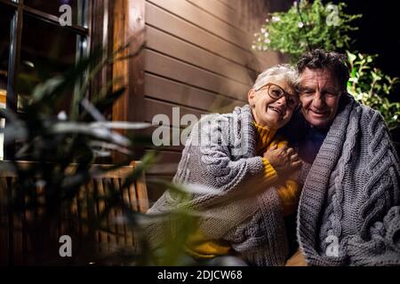 Porträt eines älteren Ehepaares, das abends auf der Terrasse sitzt und umarmt. Stockfoto