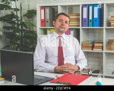 Porträt eines Mitarbeiters, Manager, der am Tisch im Büro sitzt. Stockfoto