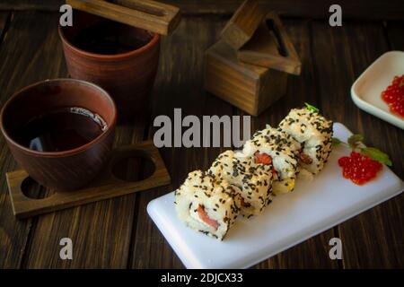 Frisches Sushi mit schwarzen und weißen Sesamsamen bedeckt Dunkler Hintergrund Stockfoto