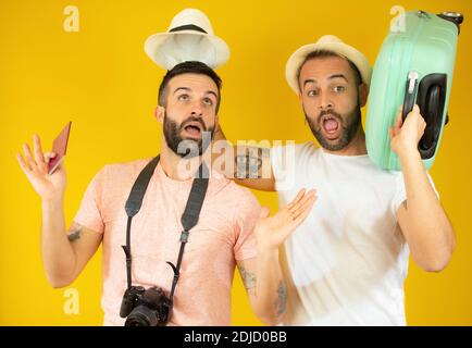 Junge Homosexuell paar von zwei Männern mit Koffer gehen auf Sommerferien über gelben Hintergrund. Stockfoto